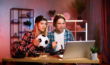 Worried young man and woman watching soccer game on wireless laptop at home.